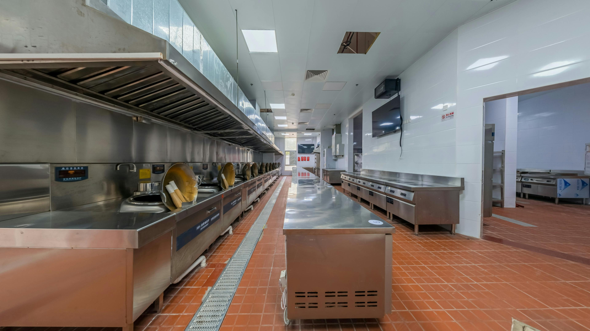 Modern industrial kitchen interior featuring stainless steel appliances and tiled flooring, ideal for commercial use.